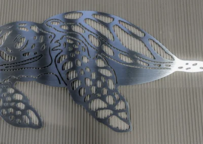 Metallic turtle sculpture with openwork shell design on a striped surface