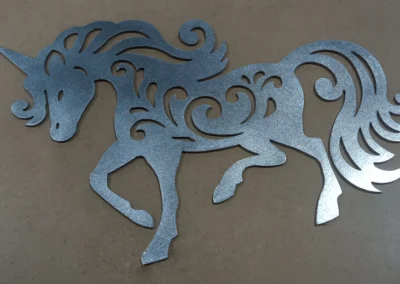 Metallic unicorn silhouette cutout with decorative swirls on a brown background